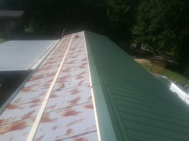 Old rusted panels beside newly installed green metal roofing — Wind Damage Roof Repair by Roofing Brothers in Trent