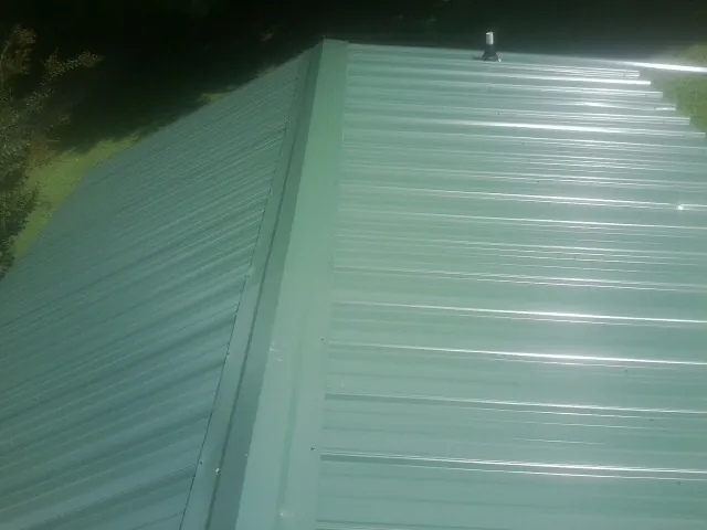 New green metal panels meeting at the ridge of a roof — Flat Roof Repair work by our crew in Trent