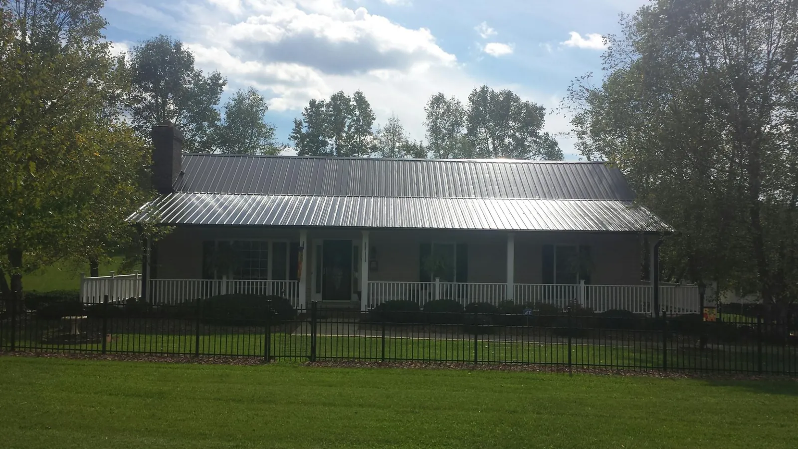 Gray metal roof on a brick ranch with a full width front porch — Gutter Guard Installation work by our crew in Trent