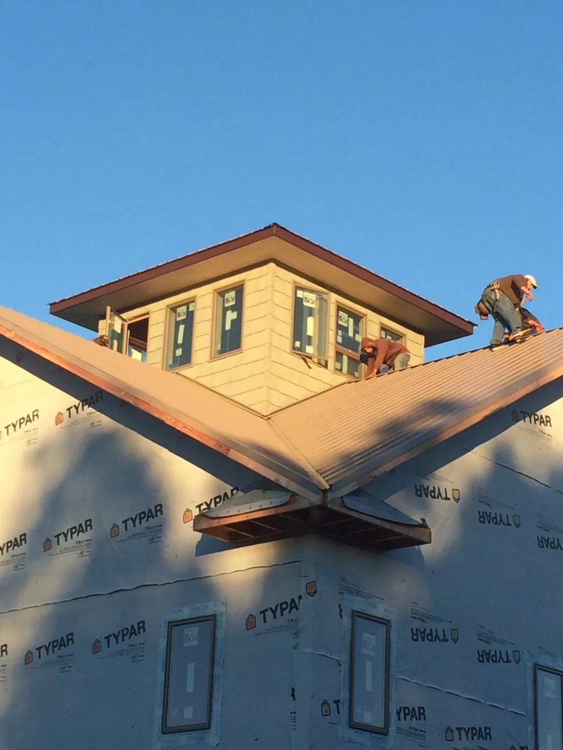 Roofers working around a rooftop cupola on a new metal roof at sunset — Roof Waterproofing in Trent by Roofing Brothers